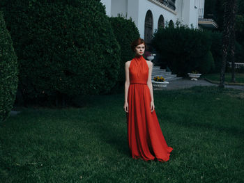 Portrait of woman standing on grass against trees