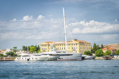 Sailboats in sea against sky in city