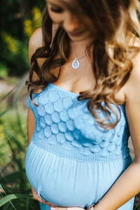 Pregnant woman wearing blue dress standing in park