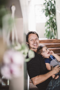 Portrait of happy father with daughter sitting on steps at home