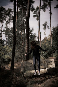 Woman jumping by sofa in forest