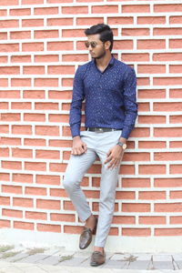 Full length of young man standing against brick wall