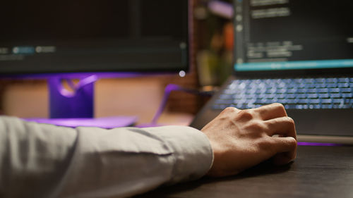 Cropped hand of man using laptop