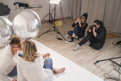 Female photographers taking pictures of couple in studio