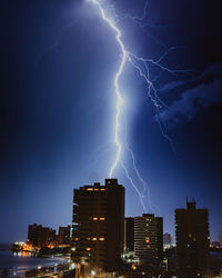 Lightning over illuminated buildings in city at night