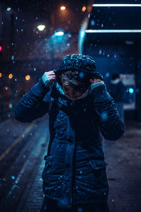 Man standing on wet illuminated during winter at night