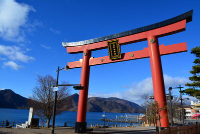 Information sign by sea against blue sky