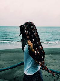 Woman standing on beach against sea against sky