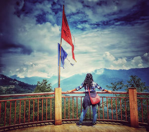 Rear view of woman standing by railing against sky