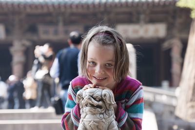 Portrait of smiling girl by statue at temple