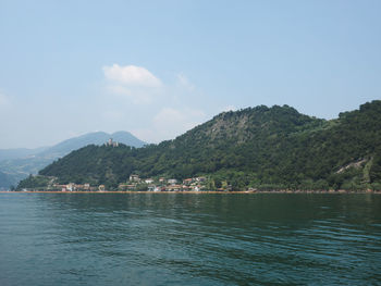 Scenic view of sea by mountains against sky