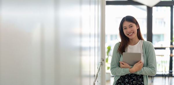Young woman standing against window