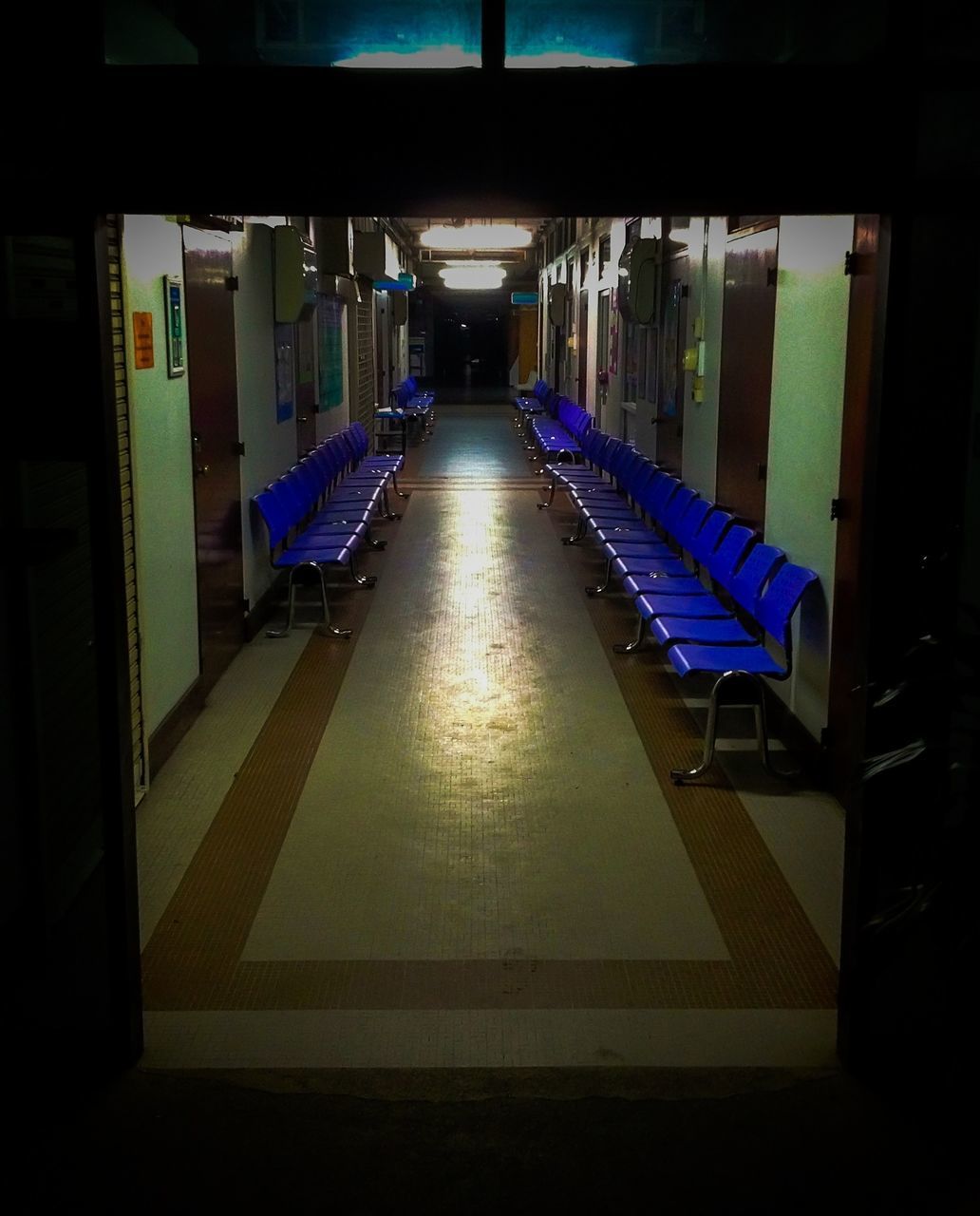 indoors, architecture, built structure, empty, the way forward, multi colored, absence, illuminated, in a row, diminishing perspective, no people, building exterior, building, flooring, railing, corridor, modern, blue, city, day