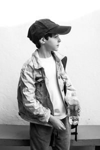 Boy holding water bottle while standing against wall