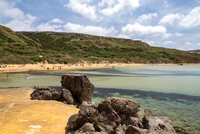 Scenic view of rocks on shore against sky