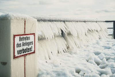 Text on snow covered land against sky