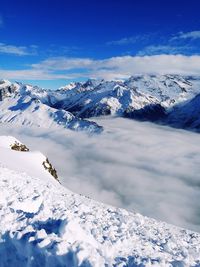 Scenic view of snowcapped mountains against blue sky