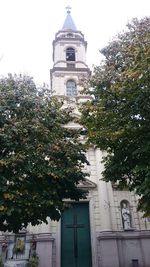 Low angle view of trees and building against sky