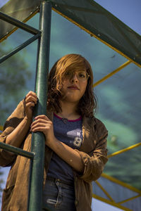 Low angle portrait of woman standing by pole