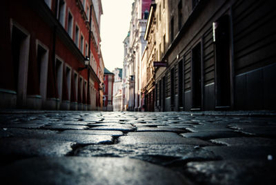 Surface level view of cobbled street amidst buildings in city