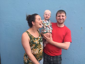 Happy family standing by wall