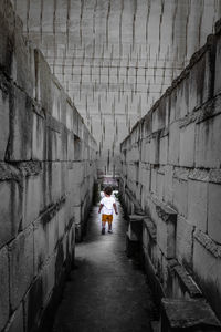 Rear view of people walking on footpath amidst buildings