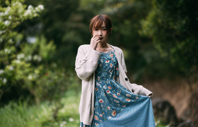 Young woman standing against trees