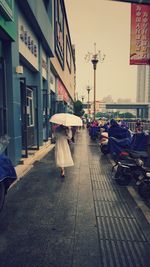 Rear view of man walking on street amidst buildings