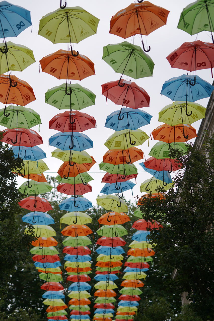 LOW ANGLE VIEW OF MULTI COLORED UMBRELLAS HANGING ON TREE