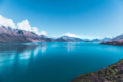 Scenic view of lake and mountains against blue sky