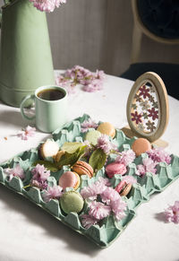 Colored macarons on the table against the background of blooming sakura and a cup of coffee, eester