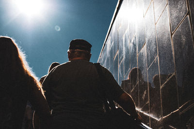 Rear view of people climbing on staircases in city during sunny day