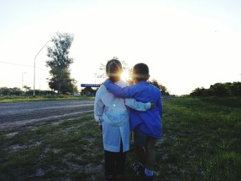 Rear view of couple on field against sky