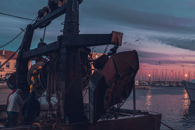 Sailboats moored in sea against sky at sunset