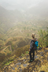 High angle view of woman standing by cliff looking at view