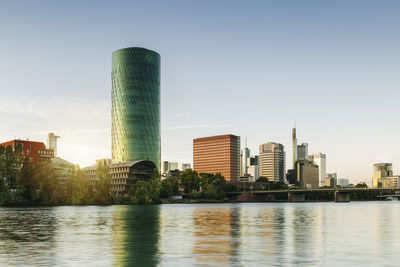 River by modern buildings against sky in city