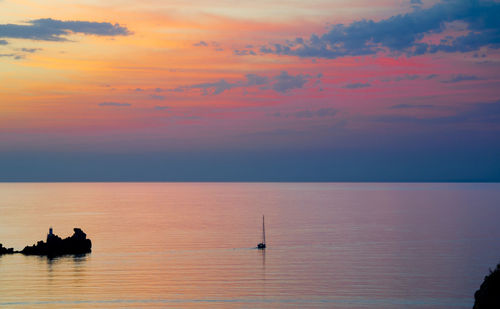 Silhouette man in sea against sky during sunset