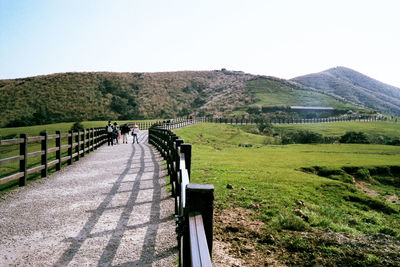 Rear view of people walking on road along landscape