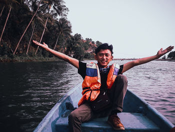 Young man sitting on boat against sky