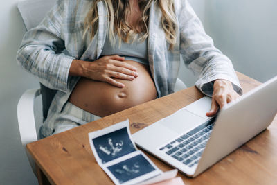 A pregnant woman holds her hand on her belly feeling the baby moving.