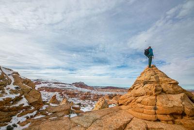 Man standing on rock against sky