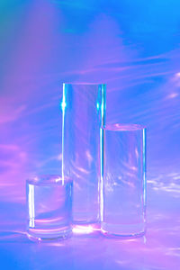 Three clear glass cylinder podiums on holographic neon background