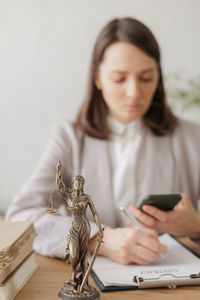 Portrait of young woman using mobile phone while sitting on table