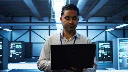 Portrait of young man using laptop at office