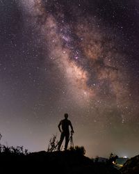 Silhouette person standing on field against sky at night