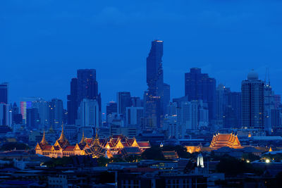 Illuminated buildings in city against sky at dusk