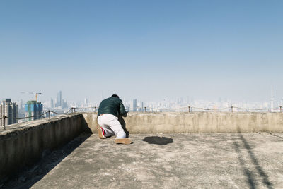 Rear view of man on retaining wall against sky