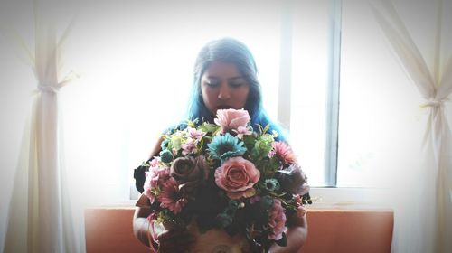Close-up of young woman holding bouquet at home