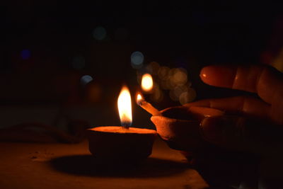 Cropped hand burning diya on retaining wall at night