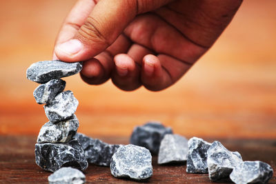 Cropped hand stacking rocks on table